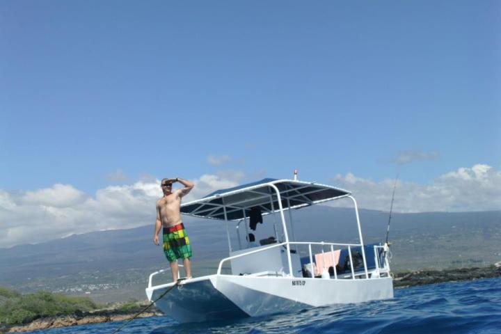 Man on private charter boat in Kealakekua Bay with view of Kailua-Kona